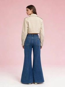 Back view of model wearing high waisted flared jeans and beige biker jacket