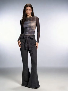 Close-up detail of high waist black denim flare jeans with matching belt and retro print top