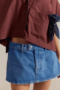 Dettaglio della minigonna in denim blu con camicia rosso scuro e bandana paisley