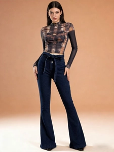 Detail view of high-waisted flared jeans with waistband tie and abstract print blouse