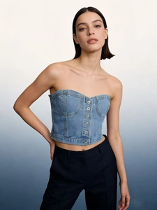 Détail d'un bustier en jean bleu clair avec boutons argentés et coutures structurées