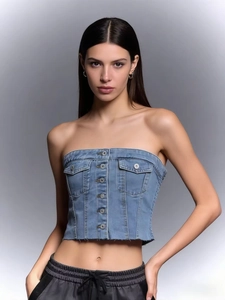Detail view of denim tube top showing metal buttons, small pockets and raw hem edges