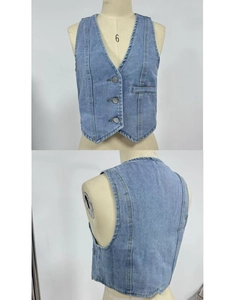 Detail view of light blue denim vest showing V-neck, buttons, and decorative pocket lines