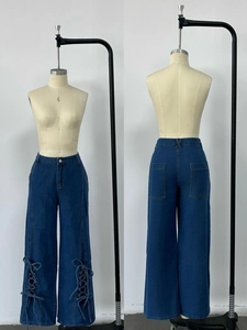 Detail of high waist dark blue wide leg jeans with unique lace-up ties on the lower hems