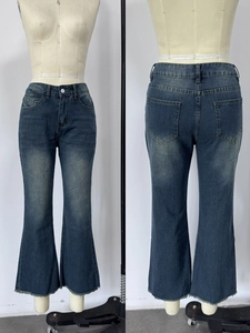Dettaglio dei jeans a zampa blu scuro con bordi a taglio vivo ed effetto lavaggio baffi