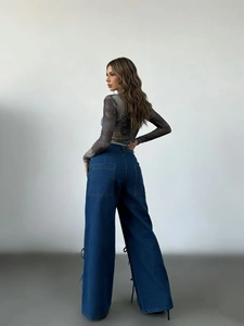 Detail of wide-leg denim jeans featuring side lace-up ties and large utility pockets