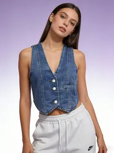 Detailed close-up of dark blue denim vest with white buttons and precise stitching