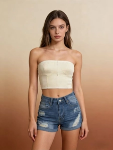 Detail view of denim shorts with ripped accents and beige corset top on a model