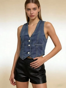 Detailed view of women's vintage blue denim vest featuring white buttons and pocket