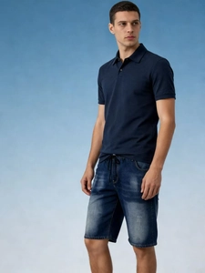 Detail view of men's casual navy polo shirt and distressed denim shorts with drawstring waist