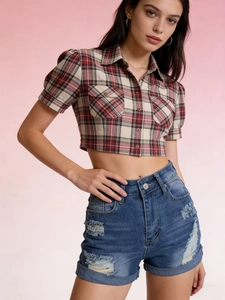 Detail of high waisted distressed denim shorts with ripped holes and frayed edges
