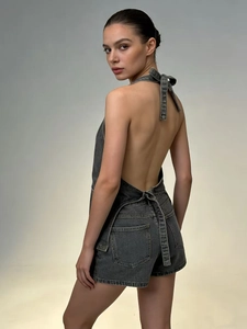 Detail view of backless dark gray denim romper showing the halter neck and pocket details