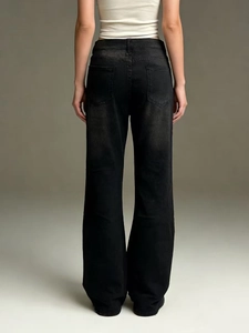 Dettaglio della trama denim nero lavato e cuciture della tasca posteriore dei jeans a zampa