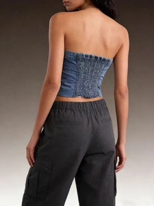 Rear view of a blue denim tube top with smocked elastic back paired with cargo pants