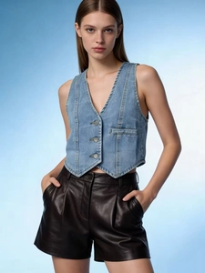 Detailed view of light blue denim vest with V-neckline and silver buttons on top