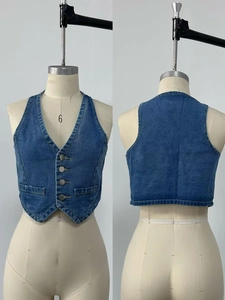 Détails d'un gilet licou en denim bleu avec boutons métalliques et poches cousues