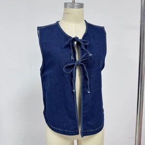 Dettaglio del gilet di jeans blu scuro con lacci frontali e cuciture a contrasto