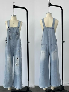 Dettaglio salopette in denim azzurro con strappi sulle ginocchia e ampia tasca frontale