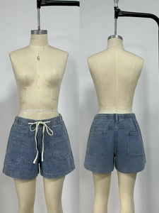 Detail view of denim shorts with elastic drawstring waist and four utility pockets