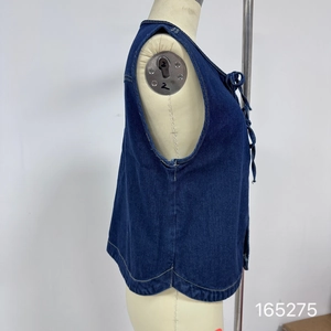 Dettaglio del gilet in denim blu scuro con lacci frontali e cuciture a contrasto