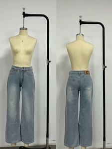 Detail view of light blue straight denim jeans with a cherry logo leather waist patch