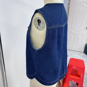 Vista laterale posteriore del gilet in denim blu scuro con cuciture gialle e lacci