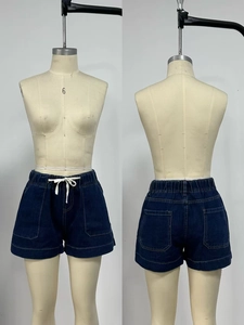 Detail view of dark blue denim shorts featuring elastic waist, white drawstring and pockets