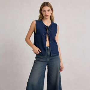 Dettaglio di un set in denim blu scuro con gilet senza maniche stringato e jeans larghi