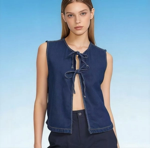 Dettaglio del gilet in denim blu scuro con lacci a fiocco e cuciture a contrasto