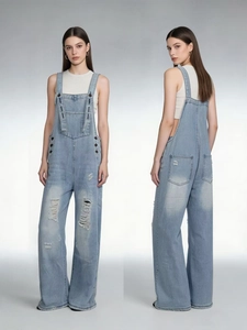 Dettaglio della salopette in denim azzurro con strappi e gamba ampia a palazzo