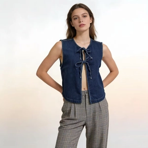 Dettaglio ravvicinato del gilet in denim blu scuro con lacci a doppio fiocco sul davanti