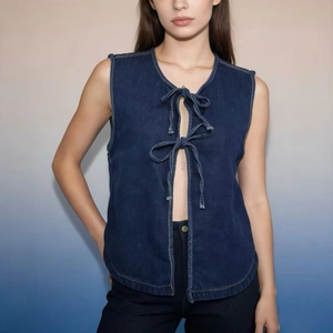 Dettaglio del gilet di jeans blu scuro con lacci frontali e design senza maniche donna