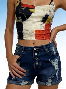 Détail du short en jean à taille haute avec quatre boutons en métal et bords déchirés
