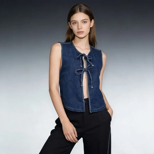 Dettaglio del gilet in denim blu scuro con chiusure a fiocco e cuciture bianche a contrasto
