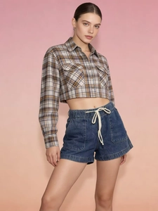 Detail of dark blue denim shorts with elastic drawstring waist and large side patch pockets