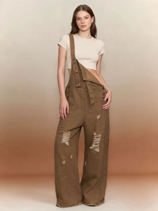 Dettaglio della salopette vintage marrone con strappi consumati e design a gamba larga