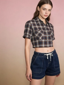 Detail of high-waisted denim shorts with elastic drawstring waist and white contrast stitching