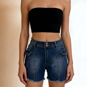 Detail of high waisted blue denim shorts with side cargo pockets and raw fringe hemline