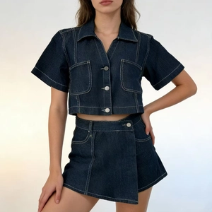 Dettaglio del set due pezzi in denim blu scuro con cuciture bianche a contrasto e bottoni argento
