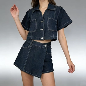 Dettaglio completo di camicia e gonna in denim blu scuro con cuciture bianche