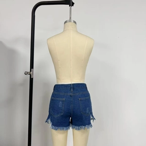 Detail view of denim shorts showing back pockets, frayed raw hem, and ripped accents