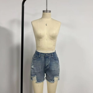 Detail of high waisted light blue denim shorts featuring ripped holes and frayed edges