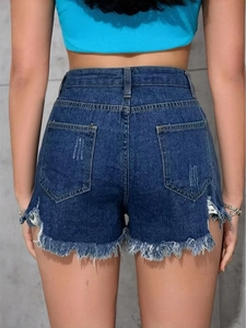 Detail view of high waisted denim shorts with fringe hem and vintage floral pattern texture
