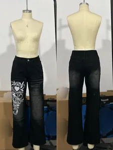 Détails d'un jean évasé noir vintage avec imprimé cœur blanc et effets de délavage naturel