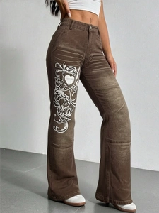 Détail d'un jean évasé marron vintage vieilli avec un imprimé tribal blanc et cœur