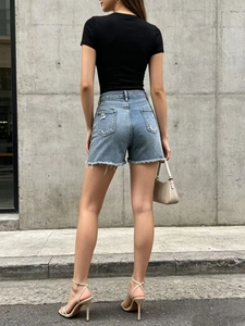 Detail of blue denim shorts featuring vintage wash, ripped pockets and frayed hem design