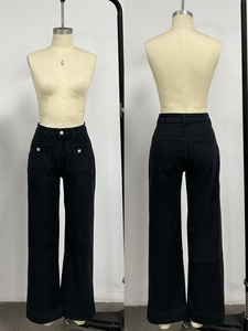 Close-up of black high-waisted jeans with large front patch pockets and white buttons