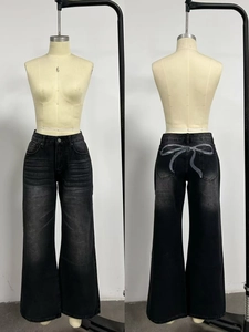 Dettaglio della stampa a fiocco bianco sulle tasche posteriori dei jeans neri lavati