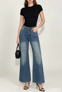 Dettaglio dei jeans in denim blu lavaggio vintage con effetto baffo e gamba larga