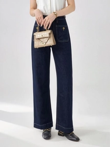 Dettaglio dei jeans blu scuro a vita alta con cuciture bianche a contrasto e ampie tasche